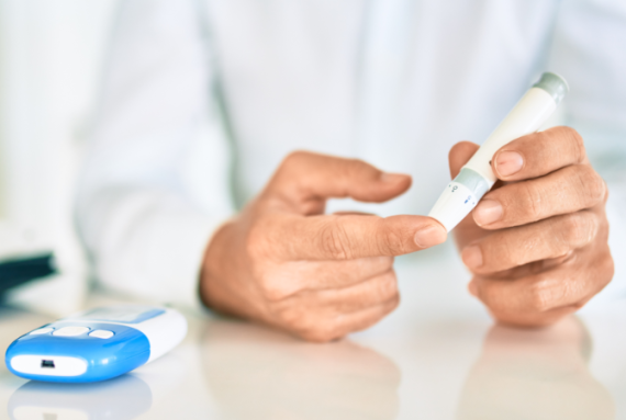 En person sidder med en fingerprikker til blodsukkermåling.