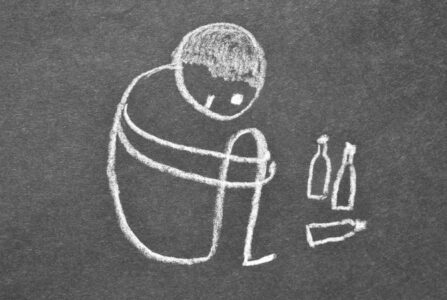 En kridttegning af en barn der sidder sammenkrøbet ved siden af 2-3 flasker.