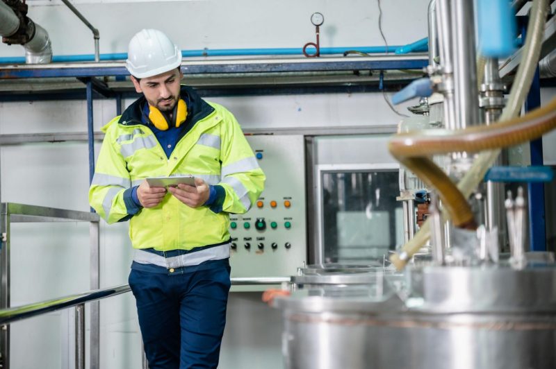 En mand med sikkerhedstøj og -hjælp står i et lokaler med teknisk udstyr.