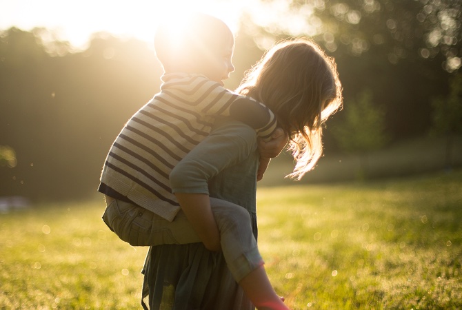 Et barn bærer et andet barn på ryggen.